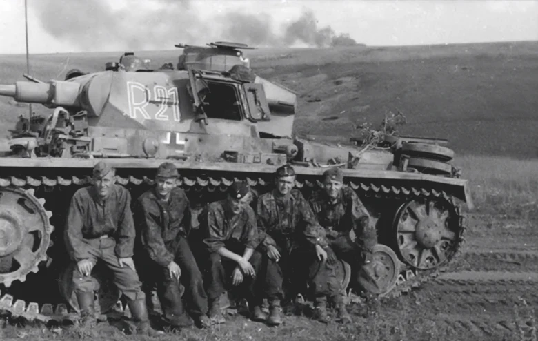 The crew of a Panzer III from the Das Reich division pose for a photograph as smoke from a recent engagement rises in the background, Kursk 1943