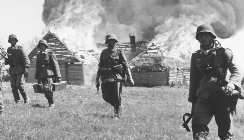 German soldiers pass through a Soviet village destroyed before their arrival as part of Stalin's Scorched Earth Policy, 1941