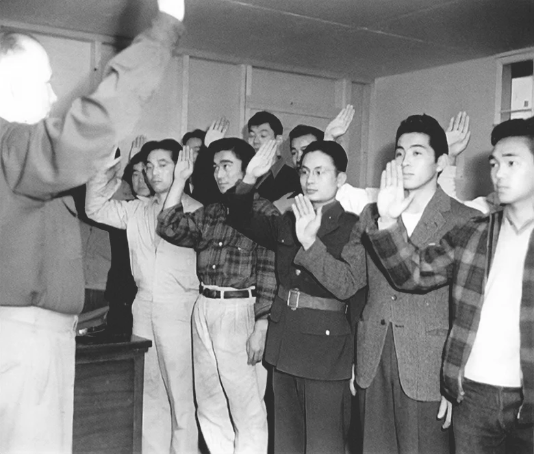 Captain Jerry P. Tobin, infantry recruiting officer, swearing in a group of Nisei youths, loyal Japanese-Americans, who are recruiting for service in the United States Army, after undergoing a stiff examination, determining their ability as interpreters on both spoken and written Japanese. All of these Nisei boys formerly held draft classification cards 4/C. There were 24 signers. December 12, 1942