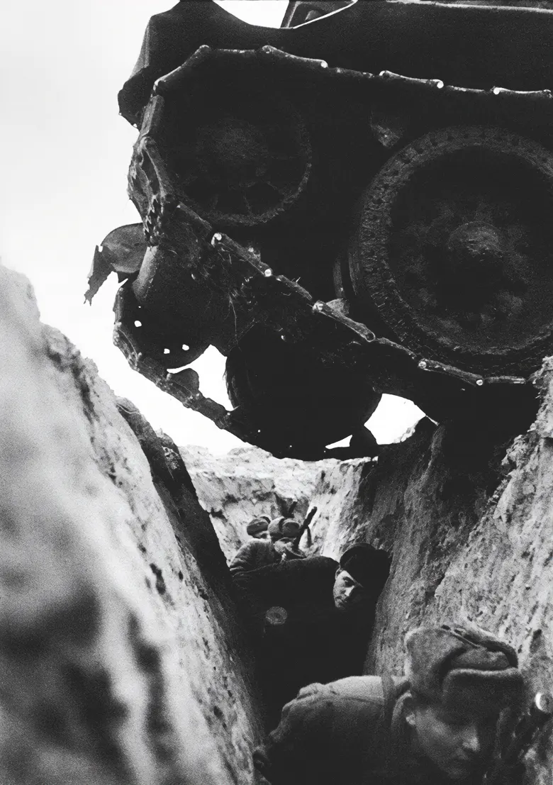 Soviet soldiers crouched in a trench as a Soviet T-34 tank passes over them during the Battle of Kursk, 1943