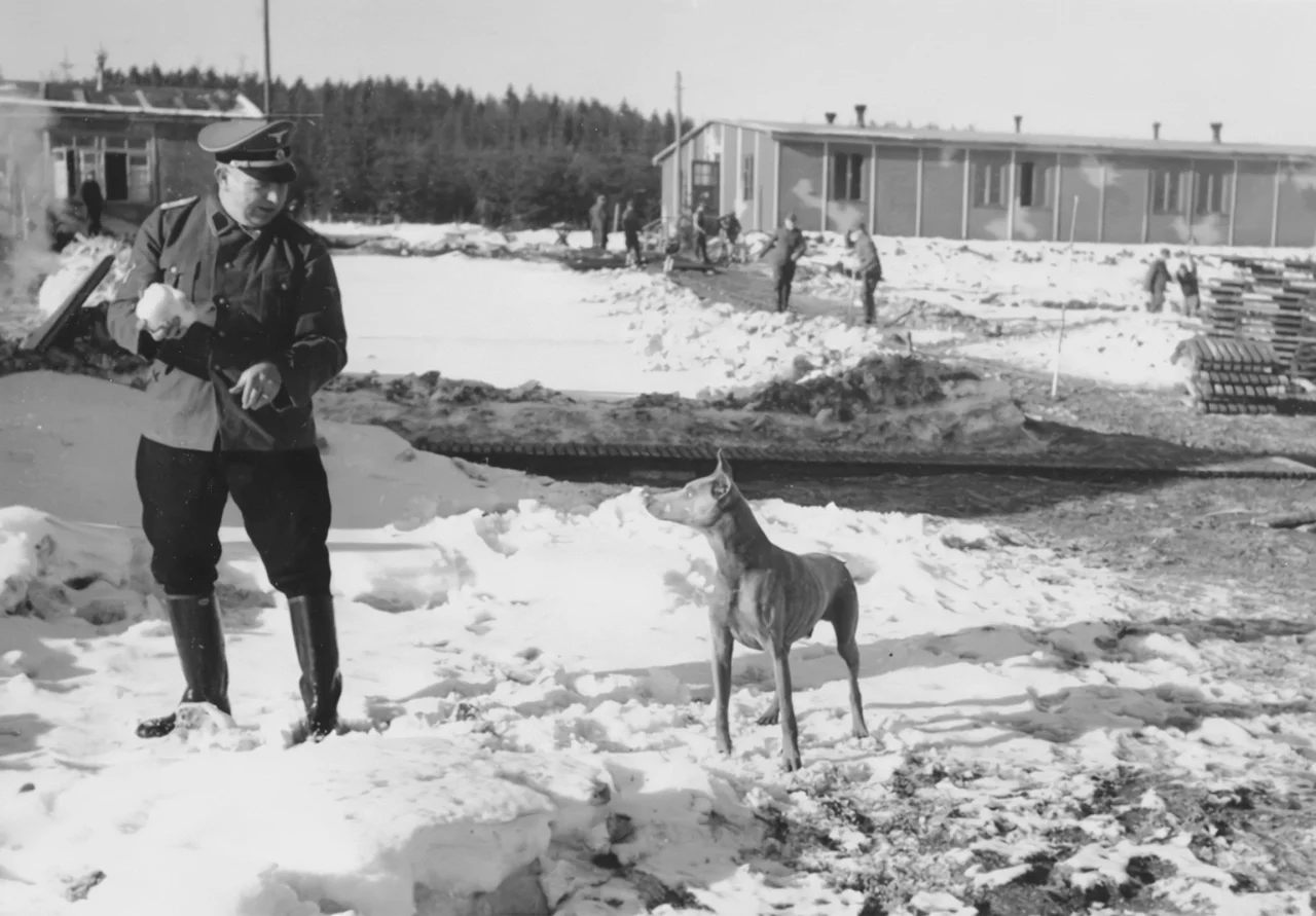 An SS officer playing with a dog in the Hinzert concentration camp